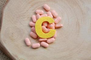 pílulas overtop de vitamina c em fundo de madeira, conceito de imunidade e nutrição foto
