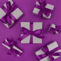 caixas de presente embrulhadas em papel artesanal com fitas roxas e laços, festivo plano monocromático foto