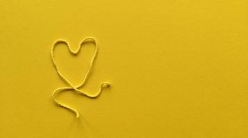 coração feito de um fio em um fundo amarelo com espaço de cópia foto