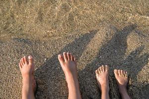 dois pares do pés em a areia. família em período de férias. pés e grãos do areia. foto