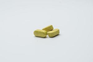 esverdeado amarelo ervas comprimidos comprimido e Castanho vidro garrafa, tradicional medicamento, orgânico pílulas isolado em uma branco fundo foto
