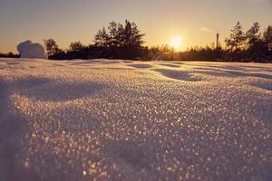 neve em primeiro plano em uma noite gelada de inverno ao pôr do sol foto