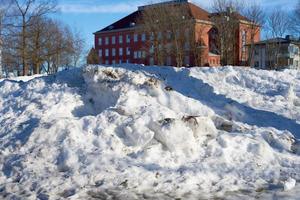 neve suja com uma velha casa de tijolos ao fundo foto