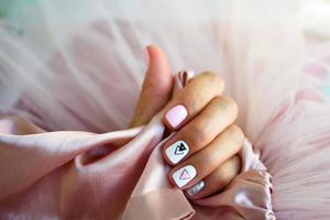 fêmea mãos com uma lindo manicure em uma Rosa fundo. foto