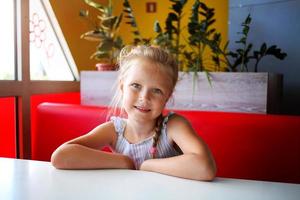 menina sentado dentro uma cafeteria e sorridente foto