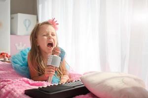 lindo pequeno menina dentro uma Princesa traje canta para dentro uma karaokê microfone. foto