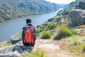 mulher caminhante sentado em dela costas com rio dentro a fundo foto