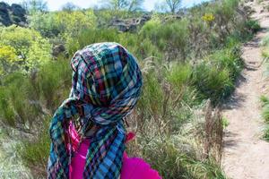 mulher caminhante em dela costas dentro a floresta com lenço de cabeça foto