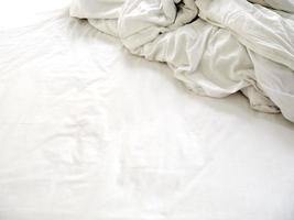 lençóis brancos em uma cama desfeita foto