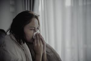 mulher asiática doente sente-se no sofá ficar em casa, a mulher se sentiu mal, queria deitar e descansar, febre alta foto