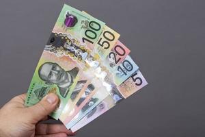 australiano dinheiro dentro a mão em uma cinzento fundo foto