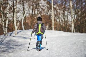 menino com esquis de turismo em estrada com neve foto