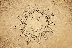 Sol forma com uma sorrir desenhado em areia foto