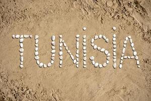 Tunísia - palavra fez com pedras em areia foto