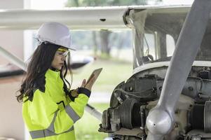 técnico consertando o motor do avião, engenharia aeroespacial feminina verificando motores de aeronaves, manutenção mecânica asiática inspeciona motor de avião foto