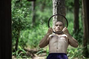 bonito homem exercícios de suspensão em uma Barra ar livre, ásia homem trens para esportivo eventos foto