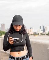 retrato turista jovem mulher ásia vestindo Preto chapéu e Preto vestir com retro filme Câmera para levar fotos. Salve  recordações do seu viaja foto