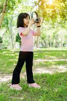 retrato do criança menina escuta para música com moderno com fones de ouvido sem fio dentro verde parque ar livre. foto