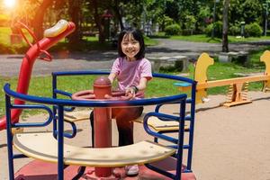 alegre criança menina jogando em Parque infantil dentro a parque. saudável verão atividade para crianças. foto