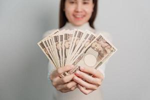 mão de uma mulher segurando a pilha de notas de iene japonês. dinheiro de mil ienes. dinheiro do japão, impostos, economia de recessão, inflação, investimento, finanças e conceitos de pagamento de compras foto