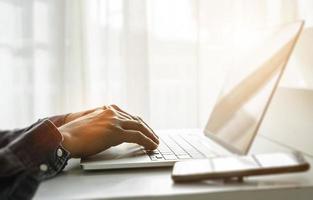 fechar acima do homem mãos usando computador portátil às casa escritório. conceito do procurando rede, navegando Informação. suave foco foto