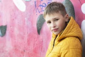 Garoto adolescente perto a parede com grafite. foto