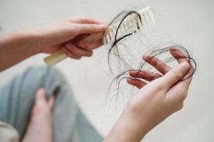 mulher asiática tem problema com perda de cabelo comprido anexado na mão.
