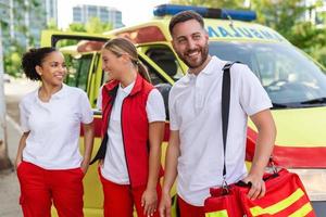 multiétnico paramédicos em pé às a de do a ambulância. emergência médico e enfermeira em pé dentro frente do ambulância foto