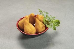 tradicional frito coxinha dentro prato em ardósia fundo, popular brasileiro lanche foto