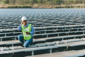 engenheiro inspetor segurando computador portátil e trabalhando dentro solar painéis poder plantar verificação fotovoltaico células e eletricidade Produção. foto