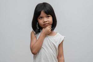 retrato de criança asiática de 5 anos e para coletar cabelos e colocar as mãos no queixo e fazer pose de pensamento em fundo branco isolado, ela é felicidade, brilho na juventude, conceito de educação foto