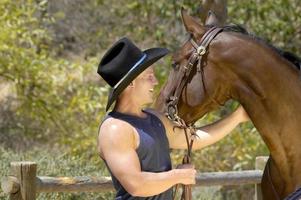 uma bonito vaqueiro leva uma perfil tiro com dele cavalo dentro uma Diversão sessão de fotos. foto