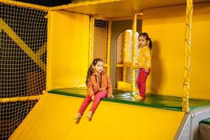 irmãos deslizante às amarelo Parque infantil parque. irmãs dentro ativo entretenimento. foto