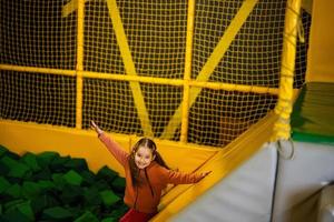 pequeno menina criança deslizar para verde suave cubos às amarelo Parque infantil parque. criança dentro ativo entretenimento. foto