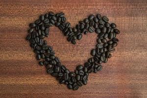 café feijão dentro coração forma em de madeira mesa foto