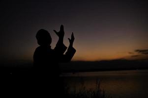 silhueta jovem ásia muçulmano homem Rezar em pôr do sol, ramadã festival conceito foto