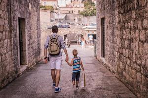 pai e filho andando pela cidade de mãos dadas foto