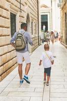 pai e filho andando pela rua da cidade velha nas férias de verão foto