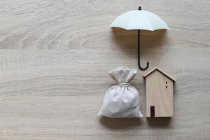 casa modelo e guarda-chuva em fundo de madeira foto