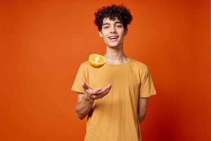 alegre encaracolado cara com laranjas dentro dele mãos frutas estilo de vida foto