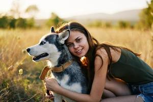 mulher sorridente e abraçando dela cachorro sentado dentro uma campo com uma dachshund cachorro sorridente enquanto gastos Tempo ao ar livre com uma amigo cachorro dentro outono às pôr do sol enquanto viajando foto