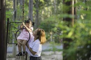 lindo jovem mãe jogar com seu filha com Diversão às Parque infantil com talento leve, feliz mãe dia,crianças dia, mãe s dia foto