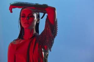 jovem mulher vermelho luz prata armaduras cadeia enviar moda azul fundo foto