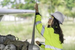 técnico consertando o motor do avião, engenharia aeroespacial feminina verificando motores de aeronaves, manutenção mecânica asiática inspeciona motor de avião foto