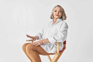 idosos mulher dentro branco camisa sentado em uma cadeira fechar-se estilo de vida foto
