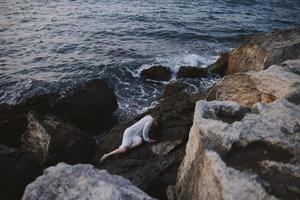 mulher dentro uma isolado local em uma selvagem rochoso costa dentro uma branco vestir inalterado foto