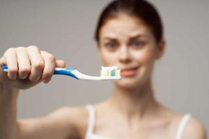 bonita mulher com uma escova de dente dentro mão manhã higiene isolado fundo foto