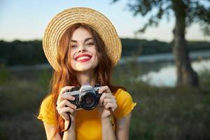 alegre mulher fotógrafo sorrir chapéu andar natureza fresco ar foto