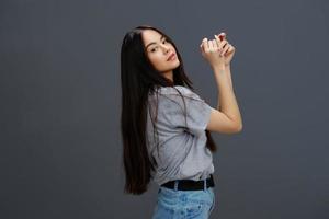 jovem mulher com grandes cabelo dentro uma cinzento camiseta gesticulando com mãos cinzento fundo foto