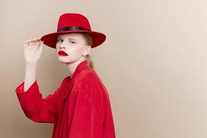 retrato do uma mulher vermelho Jaqueta e chapéu vermelho lábios moda isolado fundo foto